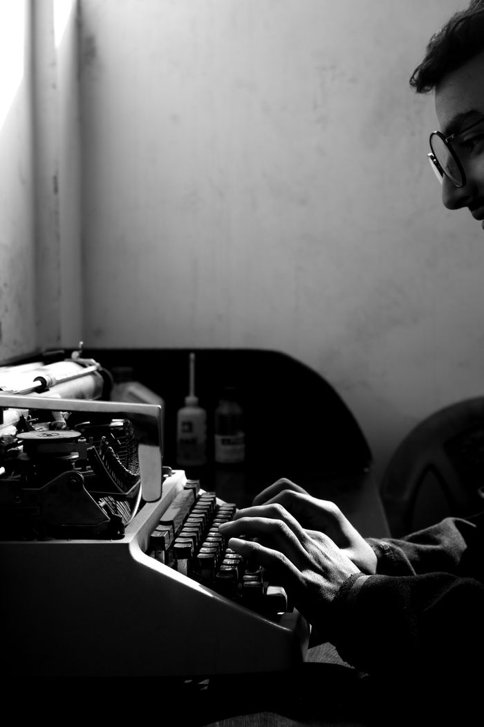 A classic black and white photo of a person typing on a vintage typewriter.