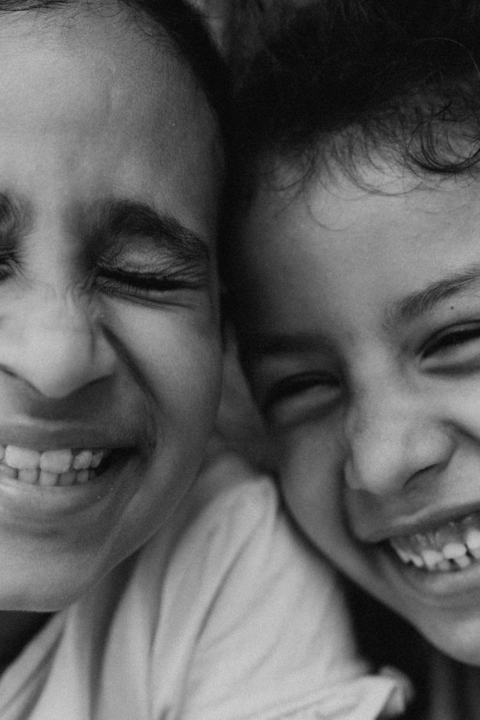A heartwarming black and white close-up of two children's joyful faces with genuine smiles.